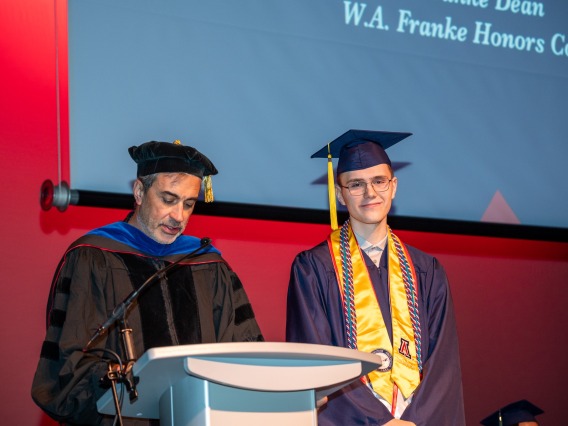 Caleb Seekins on stage with Dean John Pollard during award ceremony for the W.A. Franke Honors College Outstanding Senior award