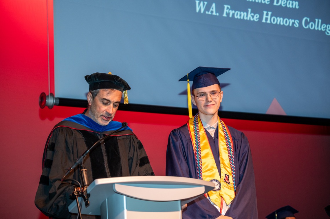 Caleb Seekins on stage with Dean John Pollard during award ceremony for the W.A. Franke Honors College Outstanding Senior award