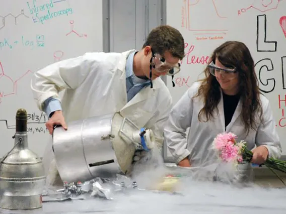 Two Students in PPE doing an experiment with flowers and liquid nitrogen