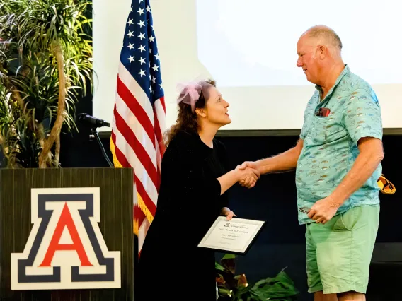 Scott Dreisbach is presented with the award on stage by Dean Carmala Garzione 