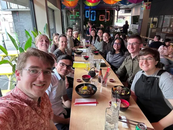 Chloe Park sitting at a long table full of smiling people in a restaurant