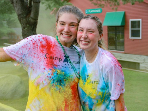 Ellie Rottier smiling with a friend with white shirts with colorful paint spatters