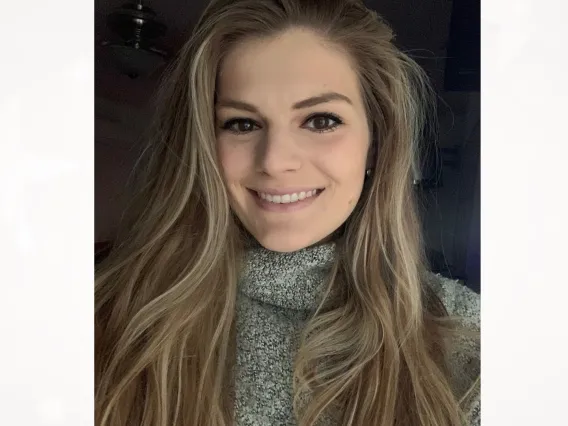 Lindsey Holmen, smiling towards the camera in front of a dark background.