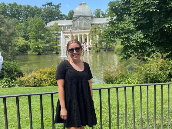 Sarah Sheperd smiling and standing in front of a large white house with a pond and fountain in front of it