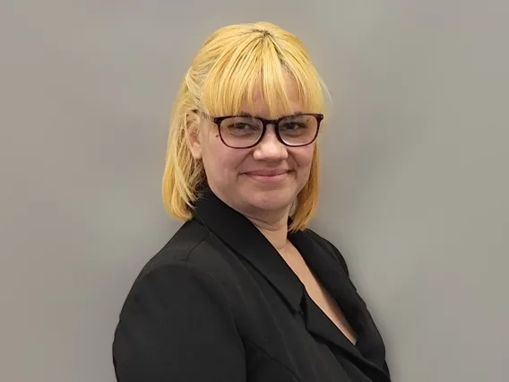 Josie Martinez wearing black glasses and a black shirt smiling towards the camera