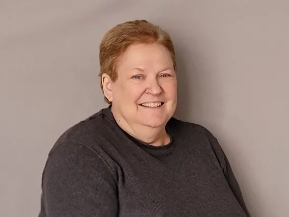 Regina Logan smiling in front of a grey background