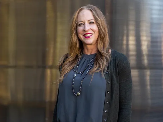 Dr. Tori Hidalgo smiling while standing in front of a smooth metallic wall