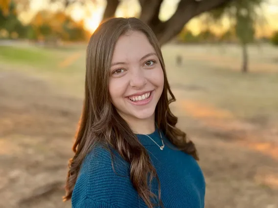 Kristen Roehling smiling towards the camera standing in front of a tree.