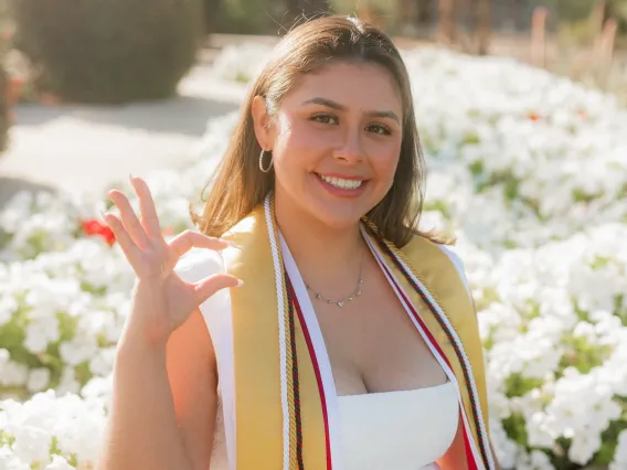 Yanely Bolanos sitting and smiling wearing a graduation sash