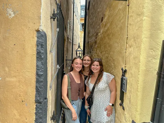 Erin Schuette smiling with two friends, standing in between two buildings