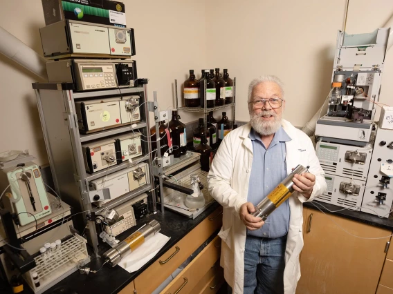 Photo of Dr. Robin Polt in lab holding a canister