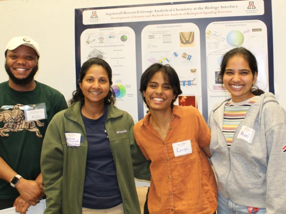 Photo of current UA grad students and a visitor in front of research poster