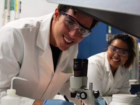 Photo Man and Woman in lab coats and protective glasses working in a UArizona CBC lab