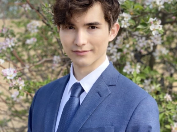 photo of Daniel Wieland in a blue suite standing in front of a tree