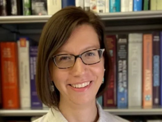 Elisa Tomat smiling in front of bookcase