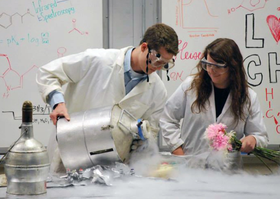 Two Students in PPE doing an experiment with flowers and liquid nitrogen