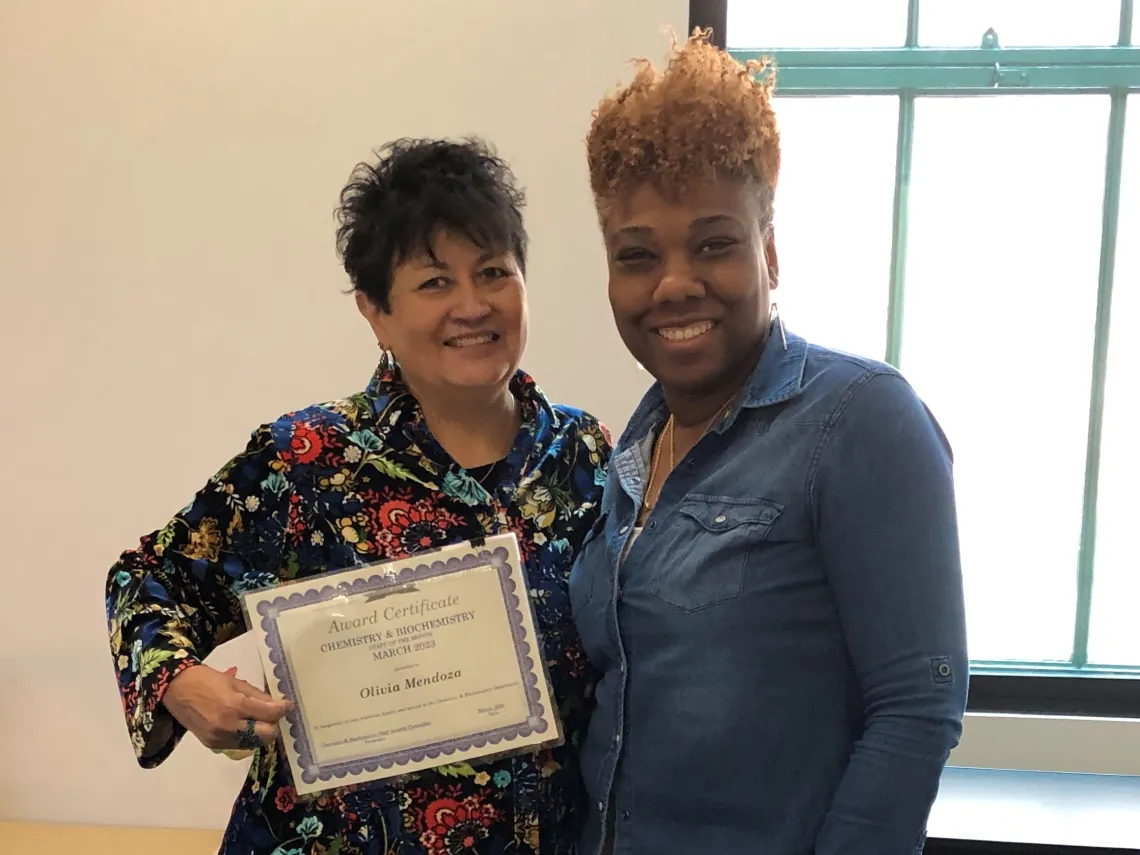 Olivia holds Staff of the Month certificate while standing next to Debra