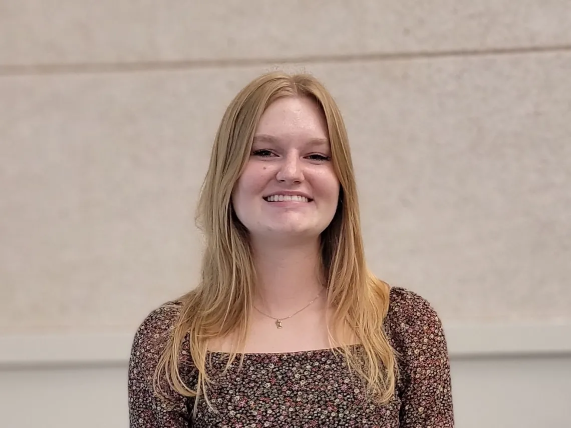 Annika Silverberg smiling towards the camera, wearing a floral dress.