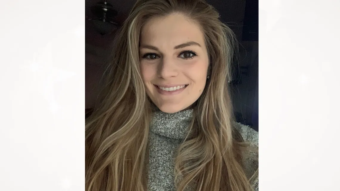 Lindsey Holmen, smiling towards the camera in front of a dark background.