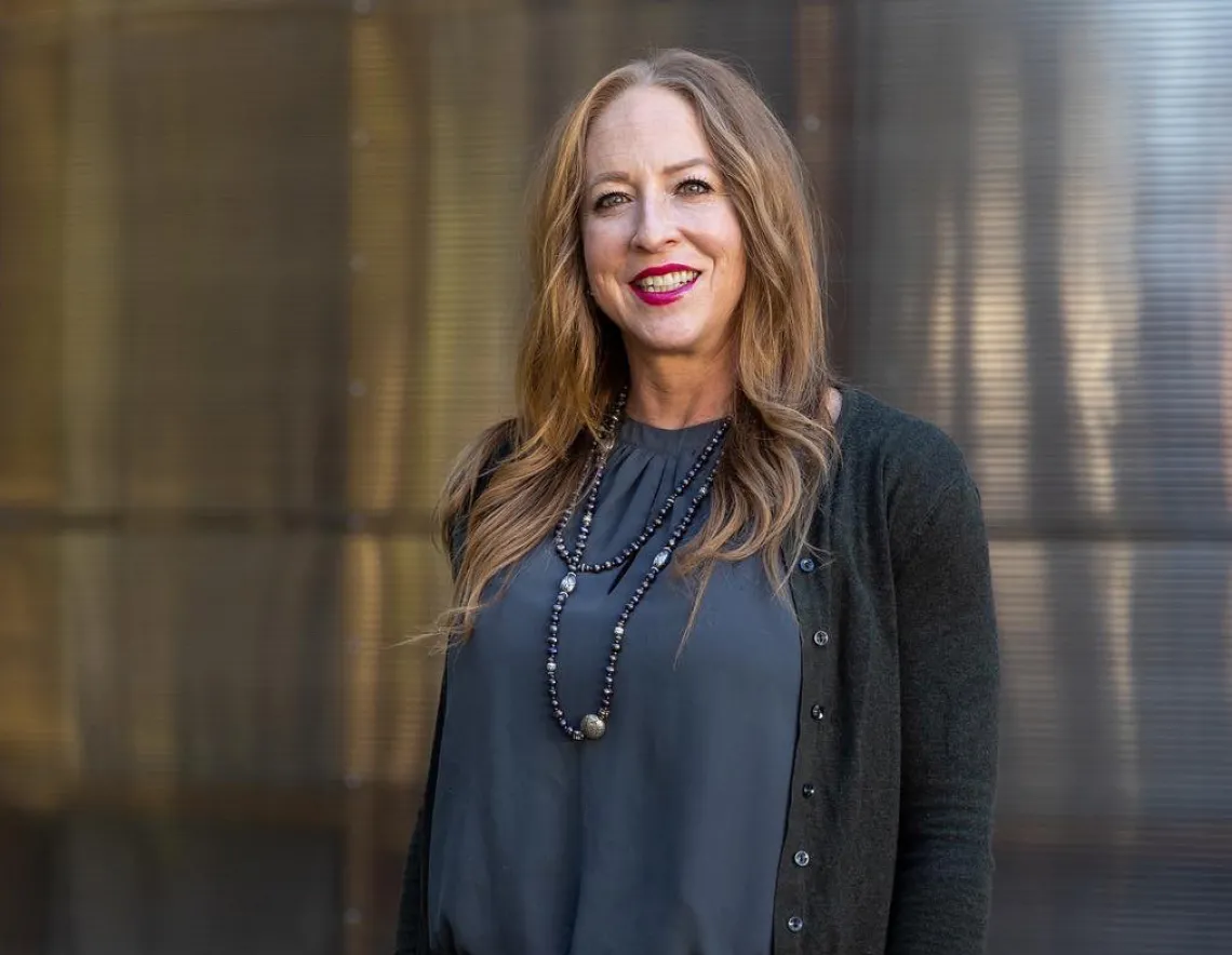 Dr. Tori Hidalgo smiling while standing in front of a smooth metallic wall