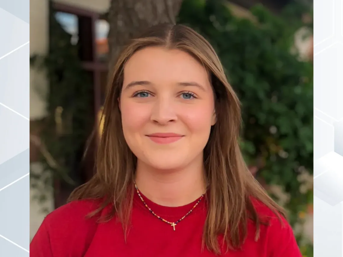 Clare Hotze, wearing a red shirt smiling towards the camera