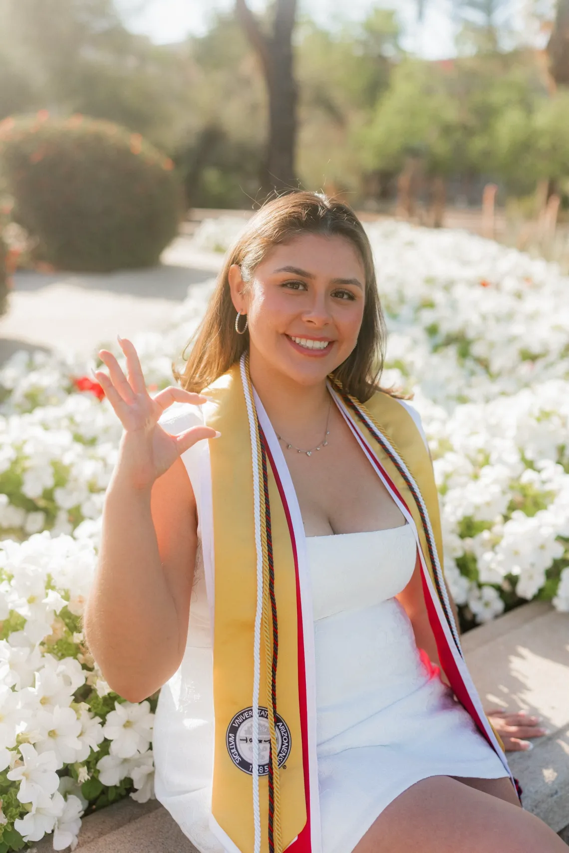 Yanely Bolanos sitting and smiling wearing a graduation sash