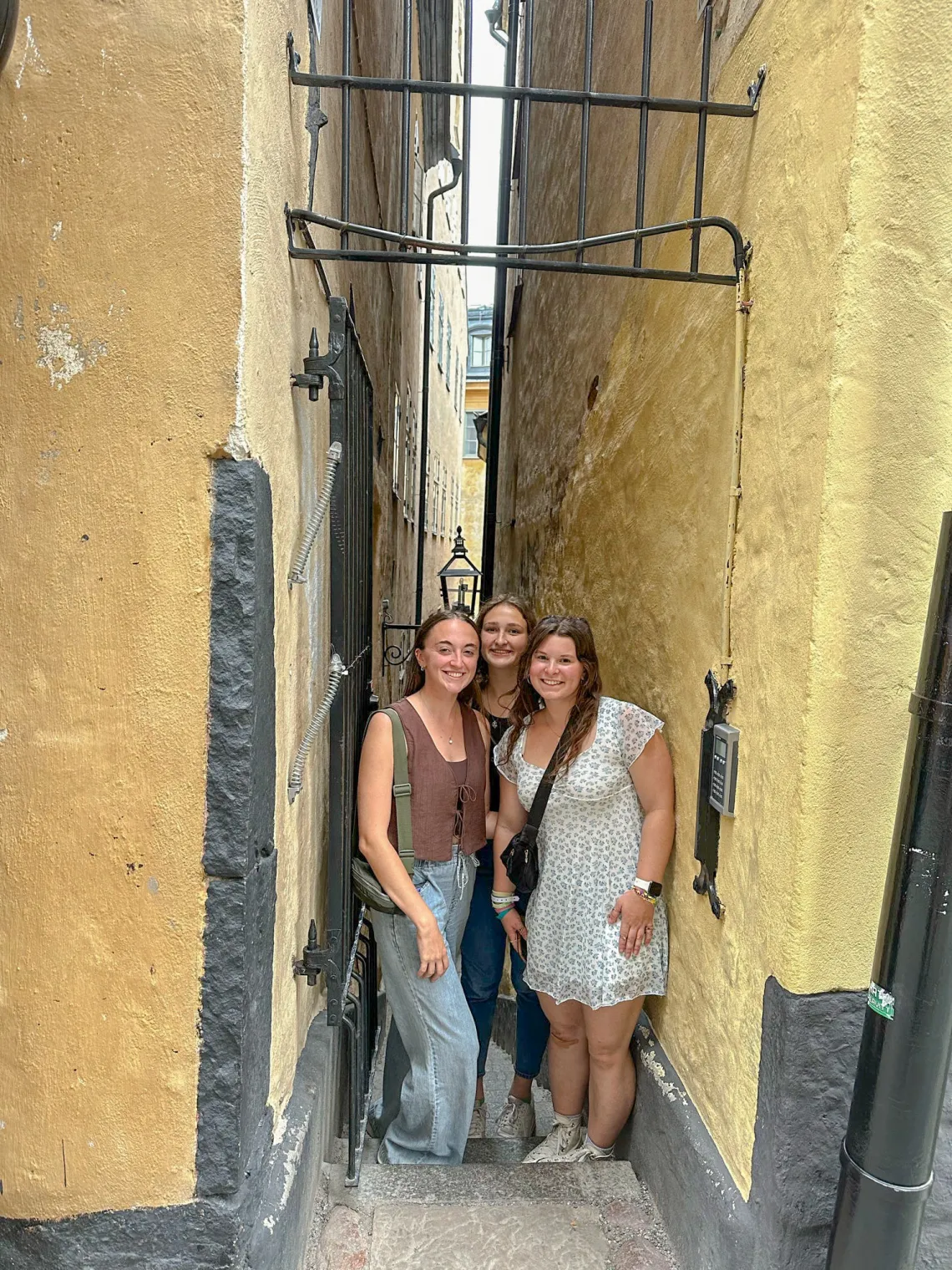 Erin Schuette smiling with two friends, standing in between two buildings