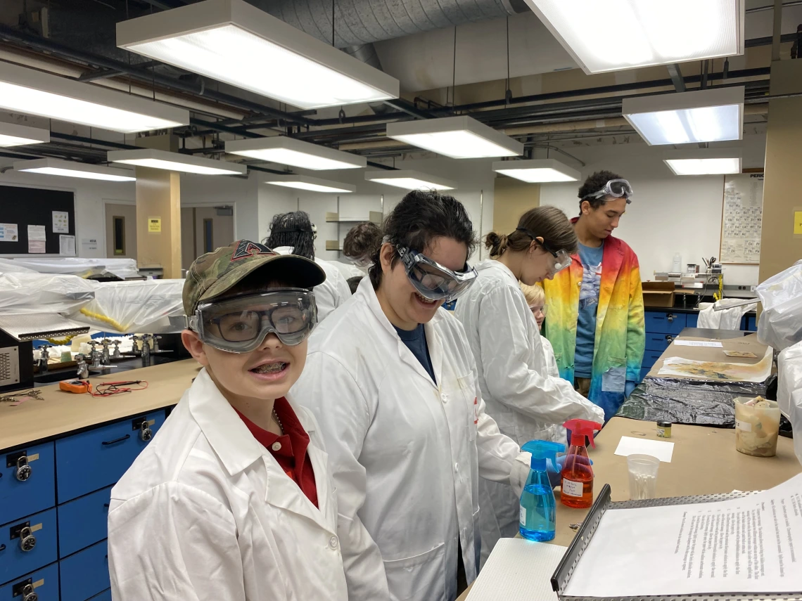 Four students wearing lab coats in a lab space.