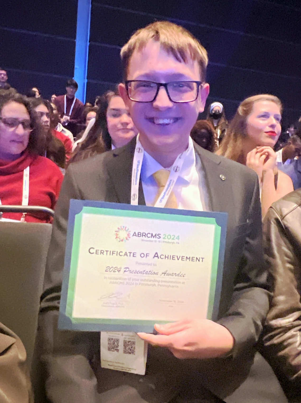 Caleb Konecek holding a certificate for his poster presentation award