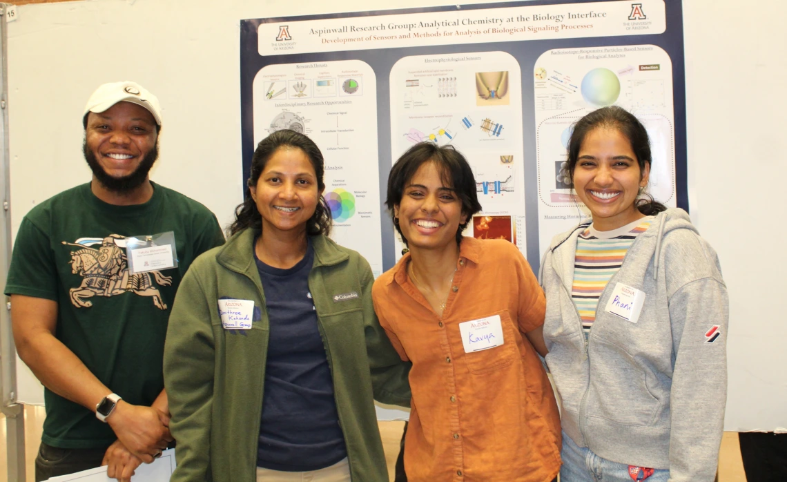 Photo of current UA grad students and a visitor in front of research poster