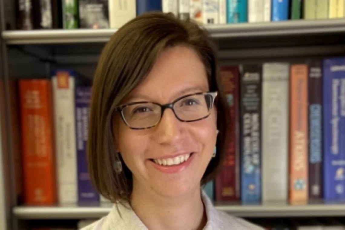 Elisa Tomat smiling in front of bookcase