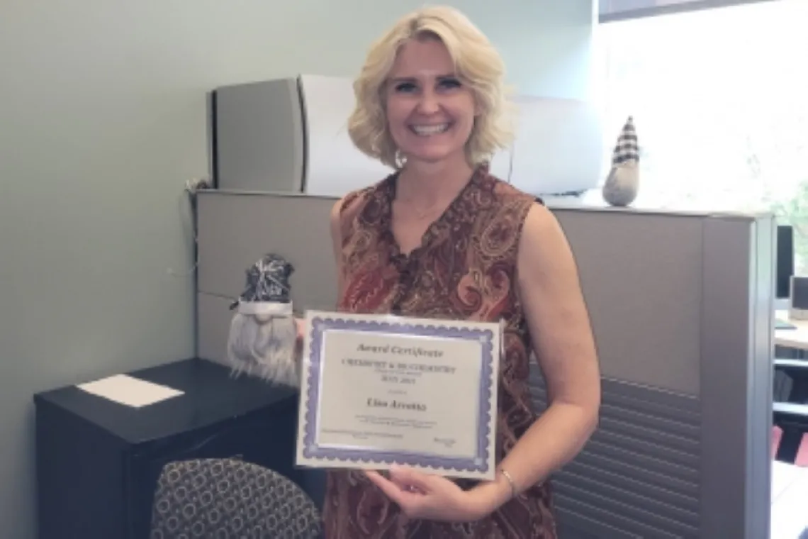 Lisa Arrotta smiling while holding up award