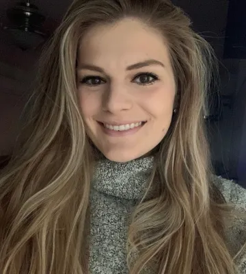 Lindsey Holmen, smiling towards the camera in front of a dark background.