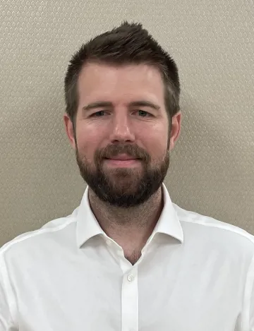 Dr. Tyler Weaver wearing a white shirt, smiling towards the camera.